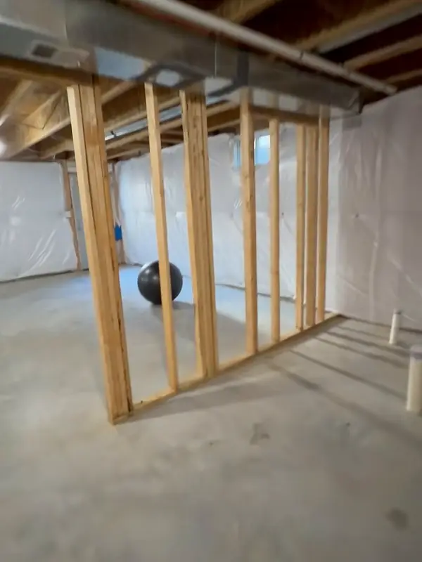 New wood studs framing a wall in an unfinished basement
